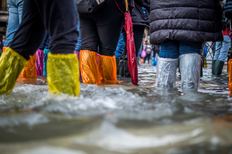Beine mit bunten Plastiküberzügen als Hochwasserschutz im Wasser watend