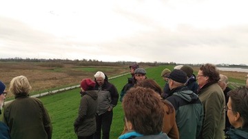 Vertreter von Land, Bund, der Landkreise Emsland und Leer, der Stadt Emden, der Meyerwerft, der Wasserverbände sowie der Naturschutzverbände BUND, NABU und WWF auf dem Emsdeich bei Coldemüntje; Heinrich Pegel (mit grauer Mütze) informiert