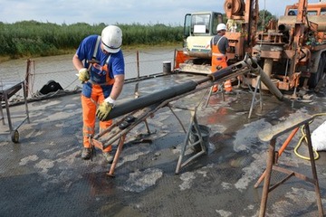 Foto 7: Bohrmeister Hartmut Köster lässt das schwere Bohrgestänge mit der frischen Meterprobe auf eine Schiene herab.