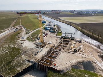 Vogelperspektive: Die Baustelle aus der Luft mit der Baugrube, in der noch das Wasser steht.