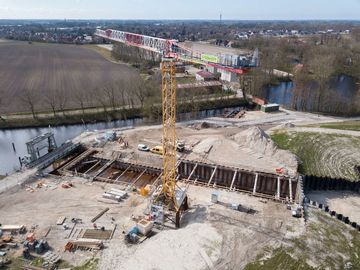 Vogelperspektive: Die Baustelle aus der Luft mit der Baugrube, in der noch das Wasser steht.