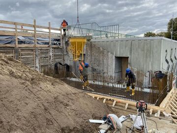 Bauarbeiter bei Betonarbeiten am neuen Betriebsgebäude - im Hintergrund ist das Sperrwerk selbst zu erkennen.