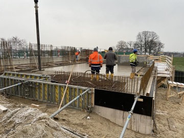 Bauarbeiter stehen an der frisch betonnierten Decke über dem Kellergeschoss.