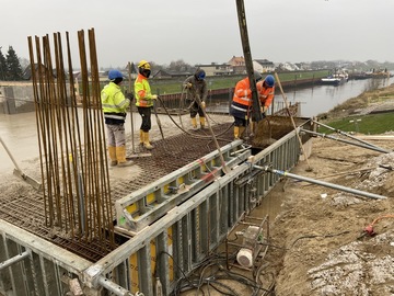 Ein Bauarbeiter führt den Schlauch, mit dem der flüssige Beton über das Stahlgittergestell gegossen wird.