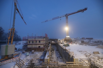 Abendaufnahme der Baustelle im Schnee links ein Baukran.