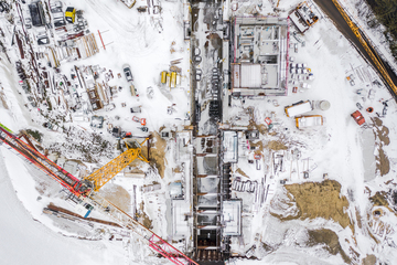 Luftbild der Kanalschleusenbaustelle im Winter. Links ein Baukran. Überall liegt Schnee. Die Schleusenkammer und das Betriebsgebäude sind bereits gut zu erkennen.