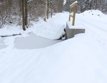 Die Großdurchlässe im Langen Damm verschwinden im Schnee. Nur das anstehende Wasser und das Geländer weisen auf die Bauwerke hin.