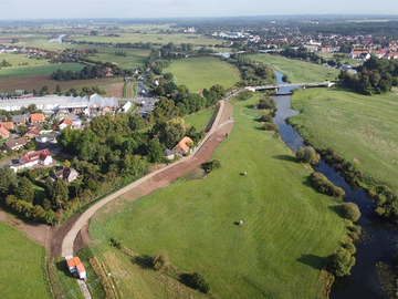 Gesamtansicht des verstärkten Deichabschnitts während der Bauzeit. Auf dem Foto wurde der Deich profiliert und auf Höhe der beiden Gebäude am Deich eine Winkelstützmauer eingebaut. Rechts im Bild die Alte und die Neue Aller mit der Altstadt von Verd