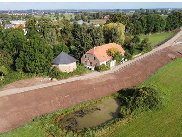 Der verstärkte und erhöhte Deich. Gebäude und Teich bzw. FFH-Schutzgebiet stellen eine Engstelle dar, für die eine technische Sonderlösung zur Herstellung der Deichsicherheit ge-wählt werden musste.