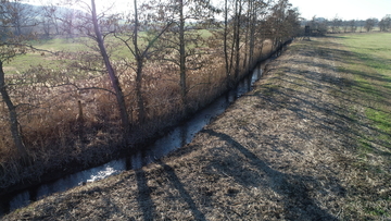 Ein Gewässer zieht sich schnurgerade durchs winterliche Bild.