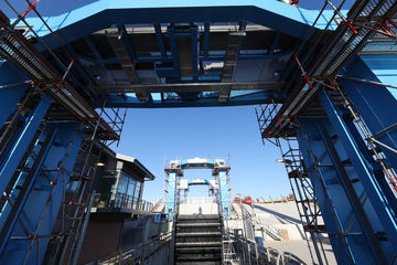 Die drei blauen Portalrahmen sind neben dem neuen Betriebsgebäude die weithin sichtbaren Elemente der neuen Schleuse. Der Portalriegel für das Binnenhaupt wurde am Samstag eingebaut (Bild: NLWKN).