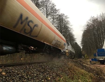 Der letzte Zug vor der geplanten Bauphase überquert die Bahntrasse. Rechts im Bild der Schwerlastenkran, dessen Abstützflächen zur Verteilung und Stabilisierung der angehobenen Lasten sorgsam vorbereitet wurden.