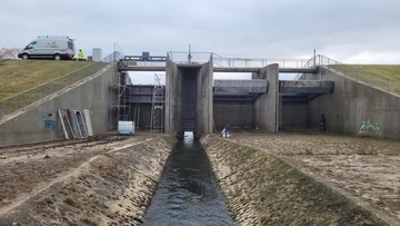 Blick aus dem Rückhaltebecken auf das Abschlussbauwerk; linkes Wehrfeld in Bearbeitung mit neuen Absenkschütz und Arbeitsgerüsten