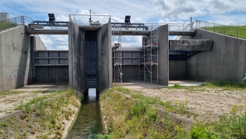 Blick aus dem Hochwasserrückhaltebecken auf das Abschlussbauwerk. Das linke und mittlere Feld mit bereits montierten Absenkschützen; das rechte Feld mit noch bestehendem Segmentverschluss. (Foto Frederik Buhr, Heidt&Peters)