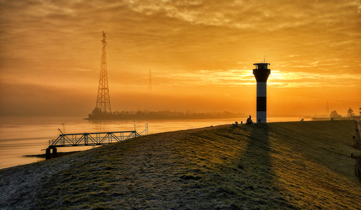 Ein Wintermorgen an der Elbe bei Stade. Im Vordergrund ein Seezeichen und der Deich, hinten der Fluss.