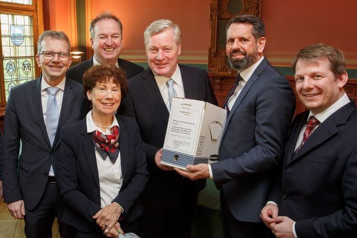 Umweltminister Olaf Lies überreicht die Beschlussunterlagen an den NPorts-Aufsichtsratsvorsitzenden und Wirtschaftsminister Bernd Althusmann. Für den NLWKN hatte Claudia Wiens das umfangreiche Genehmigungsverfahren federführend begleitet.