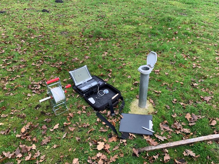 Eine Grundwassermessstelle und Gerät zur Messung auf einer Wiese ausgebreitet.