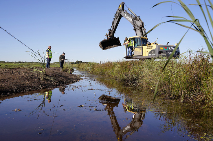 Bagger über einem Graben mit Wasser