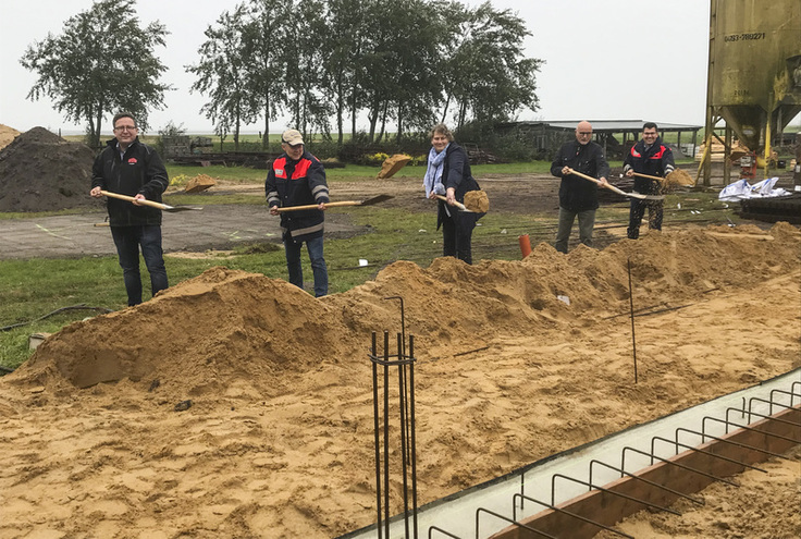 Ehrengäste beim ersten Spatenstich. Im Vordergrund ein großer Sandhaufen.