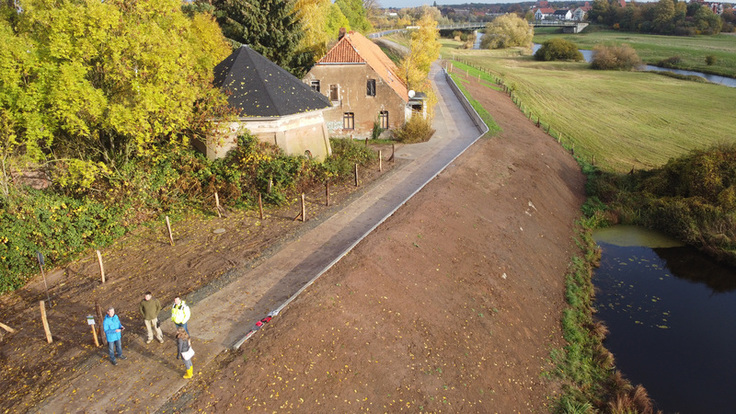 Luftbild der fertigen Baustelle: Der noch unbegrünte Allerdeich verläuft durchs Bild - auf seiner Krone sind der Deichverteidigungsweg und die Winkelstützwand gelegen.