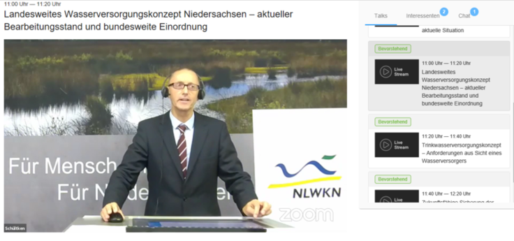 Der Moderator Hubertus Schültken steht hinter einem Moderationspult - im Hintergrund eine große Infowand mit dem NLWKN-Logo.