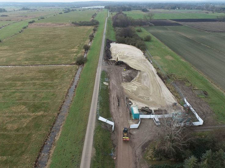 Luftbild der Fläche: Links die Elbe mit Deich, rechts ein Feld. Auf der Baustelle ist von oben eine eingeebnete Fläche zu erkennen.