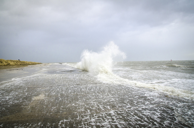 Sturmbild - eine Welle klatscht gegen das Betonwerk am Westdeich.