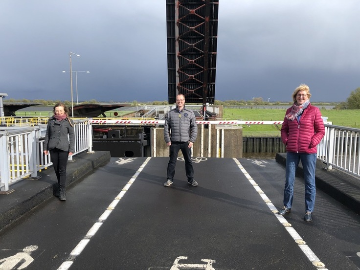 Gruppenbild auf dem Huntesperrwerk: Im Hintergrund ist die Brücke des Sperrwerks hochgeklappt.