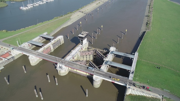 Luftbild des Huntesperrwerks - im Hintergrund sind Segelboote einer Marina zu sehen, links und rechts der schützende Deich.