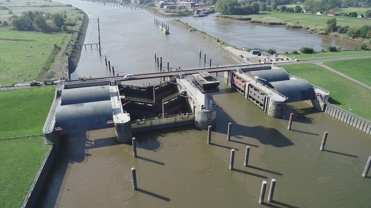 Luftbild: Das Huntesperrwerk zwischen den Deichen links und rechts der Hunte von der Weser aus gesehen.