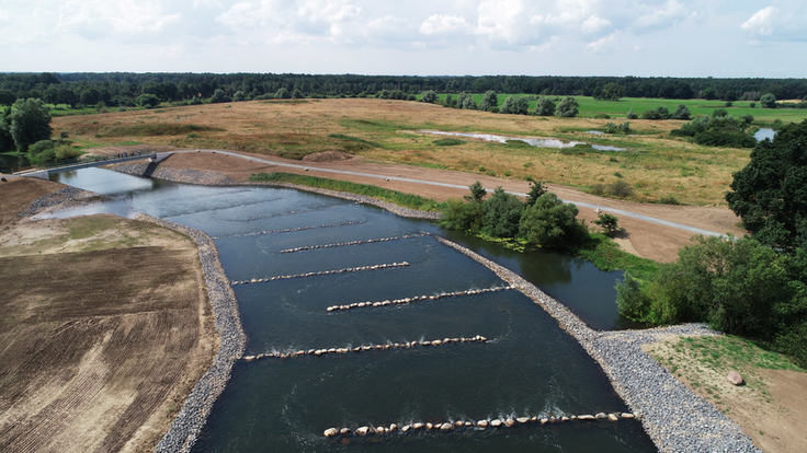 Überblick des Raugerinnes mit Berme (links), Brücke (links im Hintergrund) und Altarmstruktur (rechts). In absehbarer Zeit werden die Flächen naturnah bewachsen sein (Bild: Silke Seemann /NLWKN).