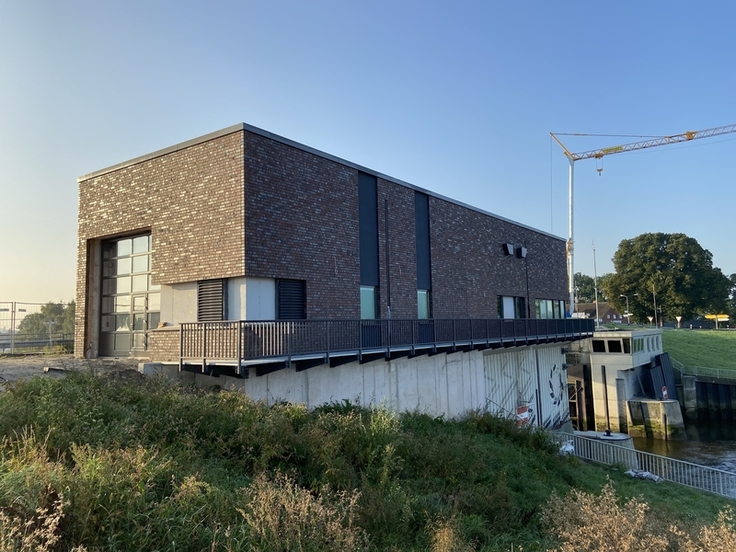 Die Grundinstandsetzung d. Ilmenau-Sperrwerks kommt gut voran. In einem ersten Bauabschnitt wurde auf seiner Nordseite ein neues Betriebsgebäude errichtet, das künftig auch die neue Anlagen- und Steuerungstechnik aufnehmen wird. (Foto: Stefan Löhn, NL