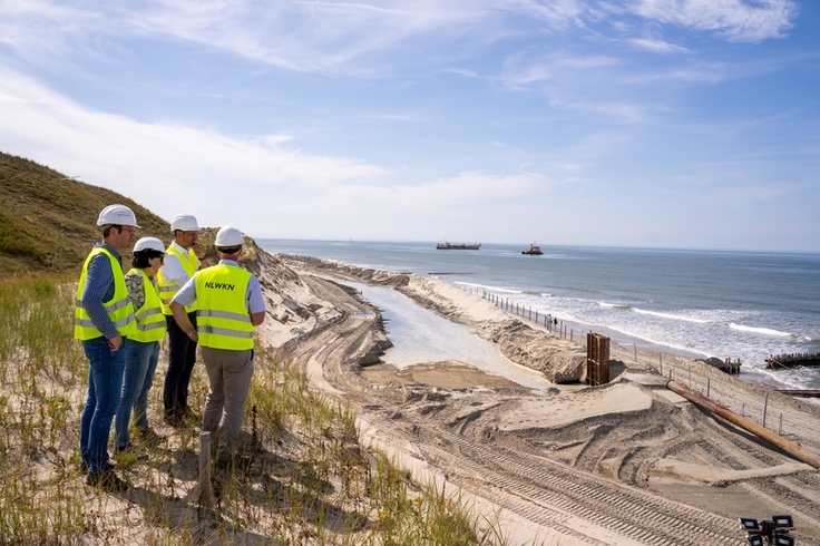 Meterhohe Abbruchkanten an der Schutzdüne hatten das außerplanmäßige Vorhaben auf Norderney notwendig gemacht. Vom Dünenkamm aus begutachtete die Gruppe das Vorankommen im 400 Meter langen Spülfeld (Bild: NLWKN/Lippe).