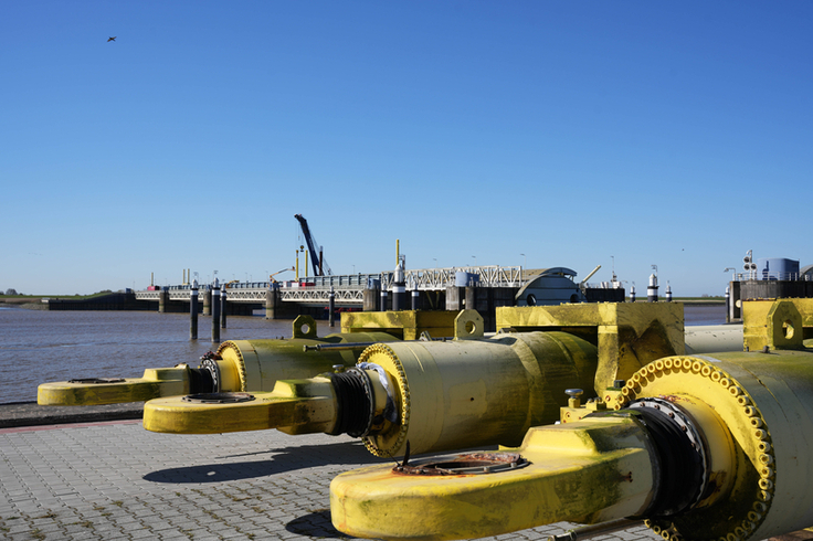An den drei jetzt ausgebauten Hydraulikzylindern sind im Bereich der Kolbenstangen deutliche Rost- und Verschleißspuren zu sehen. Sie werden in den kommenden Monaten runderneuert und kehren im Spätsommer nach Gandersum zurück (Bild: Lippe/NLWKN).