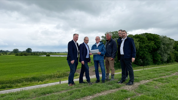 Den Deich im Blick (v.l.): Varels Bürgermeister Gerd-Christian Wagner, Rolf Neuhaus (LK Friesland), Verbandsvorsteher Peter Aengeneyndt, Thorsten Wehrmann (NLWKN), Jochen Meier (LK Friesland) und Landrat Sven Ambrosy (Foto: Romina Desenz/LK Friesland)