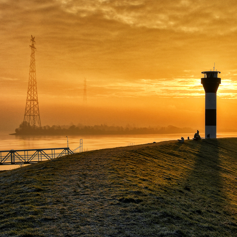 Ein Wintermorgen an der Elbe bei Stade. Im Vordergrund ein Seezeichen und der Deich, hinten der Fluss.