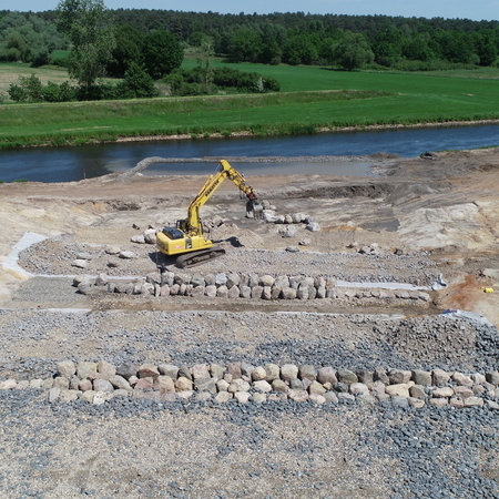 Luftbild: Vorne sind Arbeiten an der neuen Sohle des Raugerinnes erkennbar, während hinten der Fluss in seinem alten, begradigten Bett vorbeifließt.