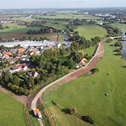 Gesamtansicht des verstärkten Deichabschnitts während der Bauzeit. Auf dem Foto wurde der Deich profiliert und auf Höhe der beiden Gebäude am Deich eine Winkelstützmauer eingebaut. Rechts im Bild die Alte und die Neue Aller mit der Altstadt von Verd